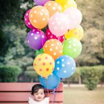 1 year sitting baby photoshoot outdoor garden white dress colorful ballons pops