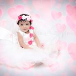 1 year sitting baby photoshoot indoor home white frill frock flowers tiara and floating hearts