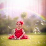 1 year sitting baby photoshoot outdoor garden red frill frock flowers red tiara rainbow bubbles