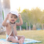 1 year sitting baby photoshoot outdoor garder wearing tie cap diaper smile sunset