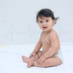 1 year sitting baby photoshoot indoor home silky hairs smiling pose in diaper
