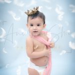 1 year poser baby photography, home, props, girl in diaper, pink wrapper, crown, falling feather, anubhavshaphotography