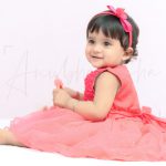 1 year sitting baby photoshoot indoor home red frill frock with red tiara happy theme