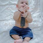 1 year sitter baby boy photoshoot home wearing blue tie smiling blue denim white background
