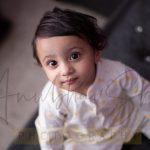 1 year baby photoshoot indoor home, posing upward white yellow romper, smiling kid