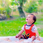1 year baby photoshoot outdoor park wearing red galice dress green trees bubbles
